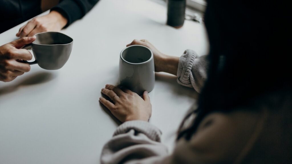 テーブルでマグカップを持ちながら向き合う二人の手元