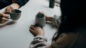 テーブルでマグカップを持ちながら向き合う二人の手元