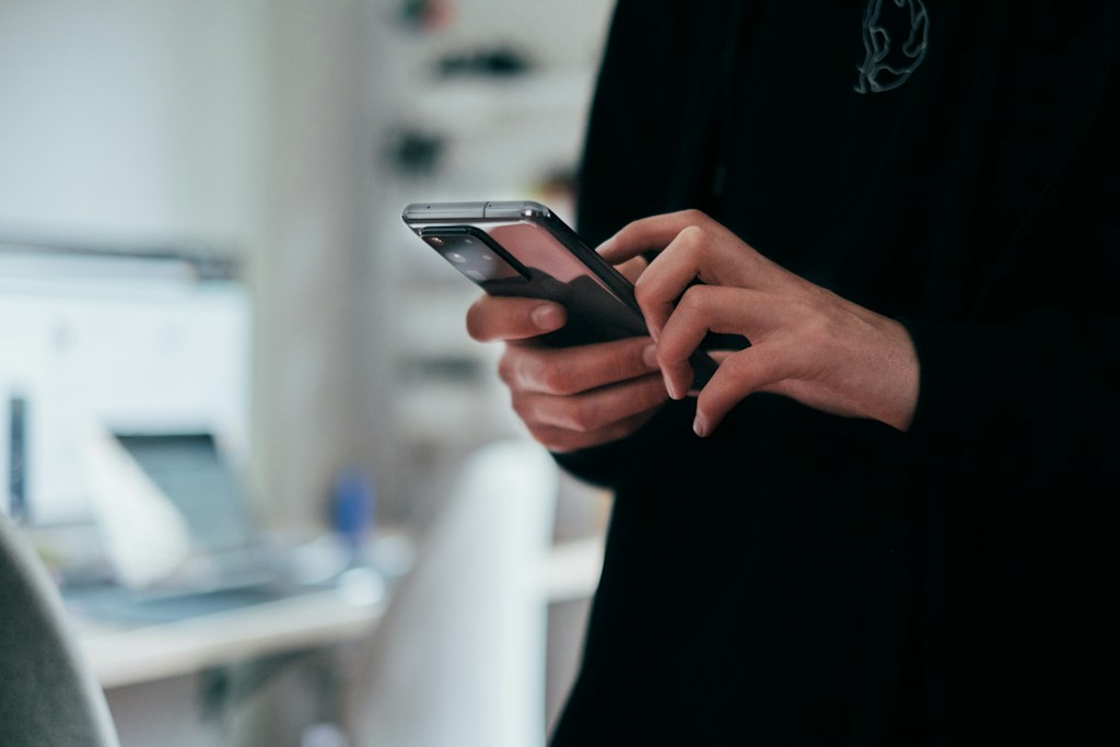 スマートフォンを両手で操作する人の手元