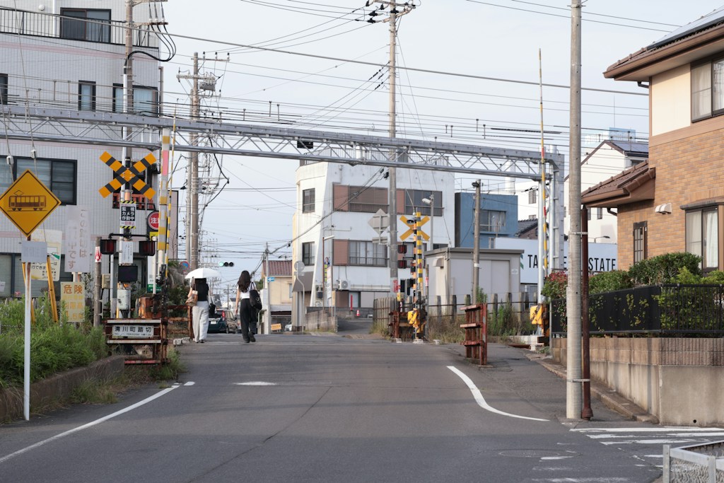 住宅街の踏切へ続く道路と注意標識