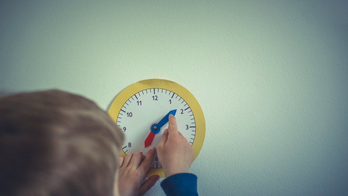 時計の針を動かして時間を確認する子どもの手