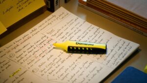 手書きの学習ノートに置かれた黄色の蛍光ペン