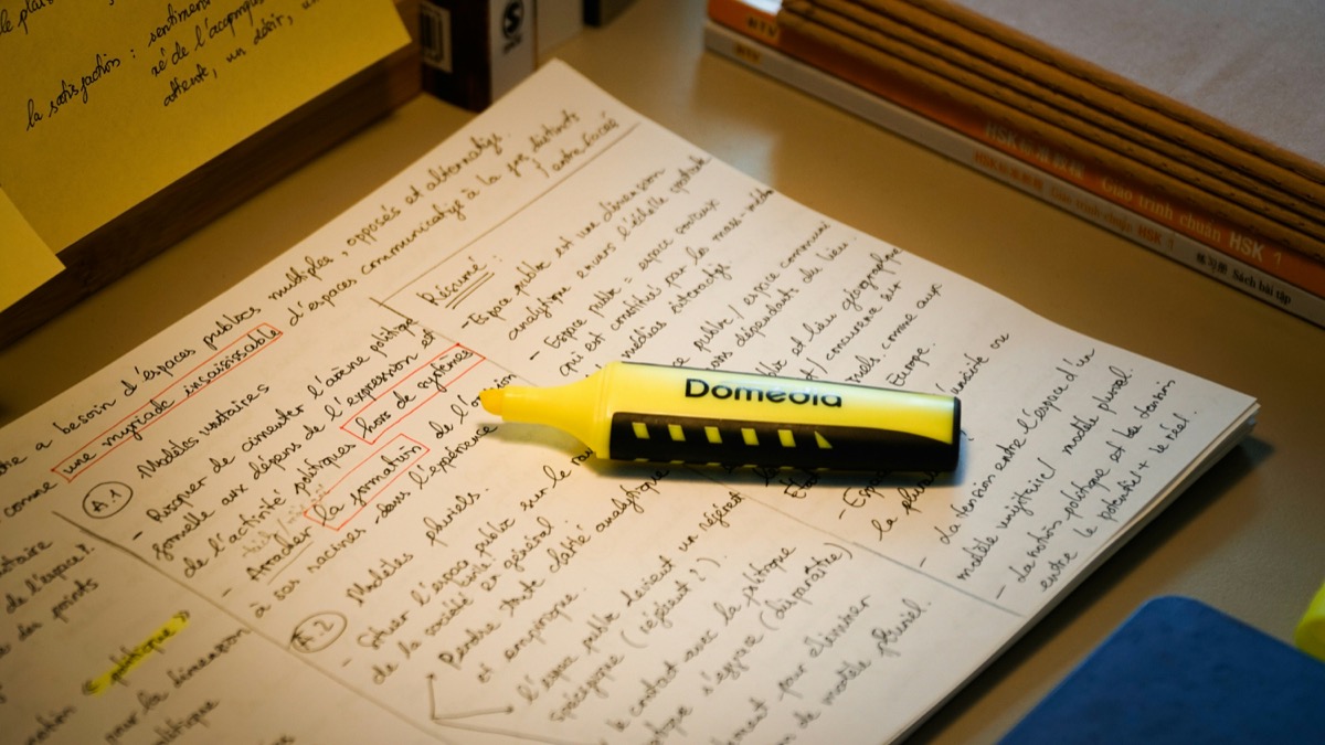 手書きの学習ノートに置かれた黄色の蛍光ペン
